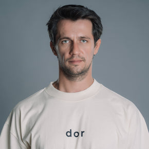 Man wearing a Natural RAW tshirt with 'dor' logo against a gray background