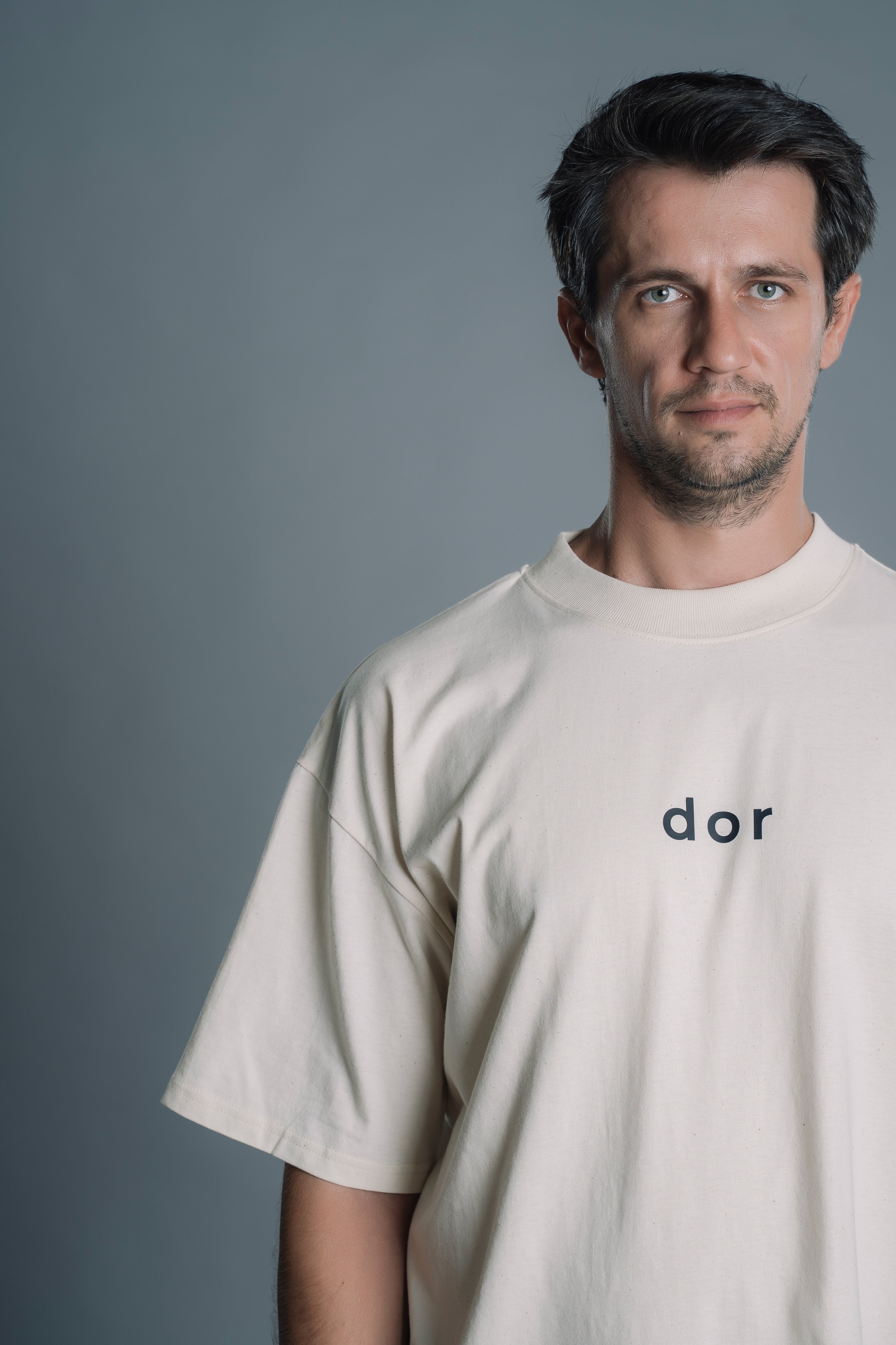 Man wearing a Natural RAW t-shirt with 'dor' logo against a gray background