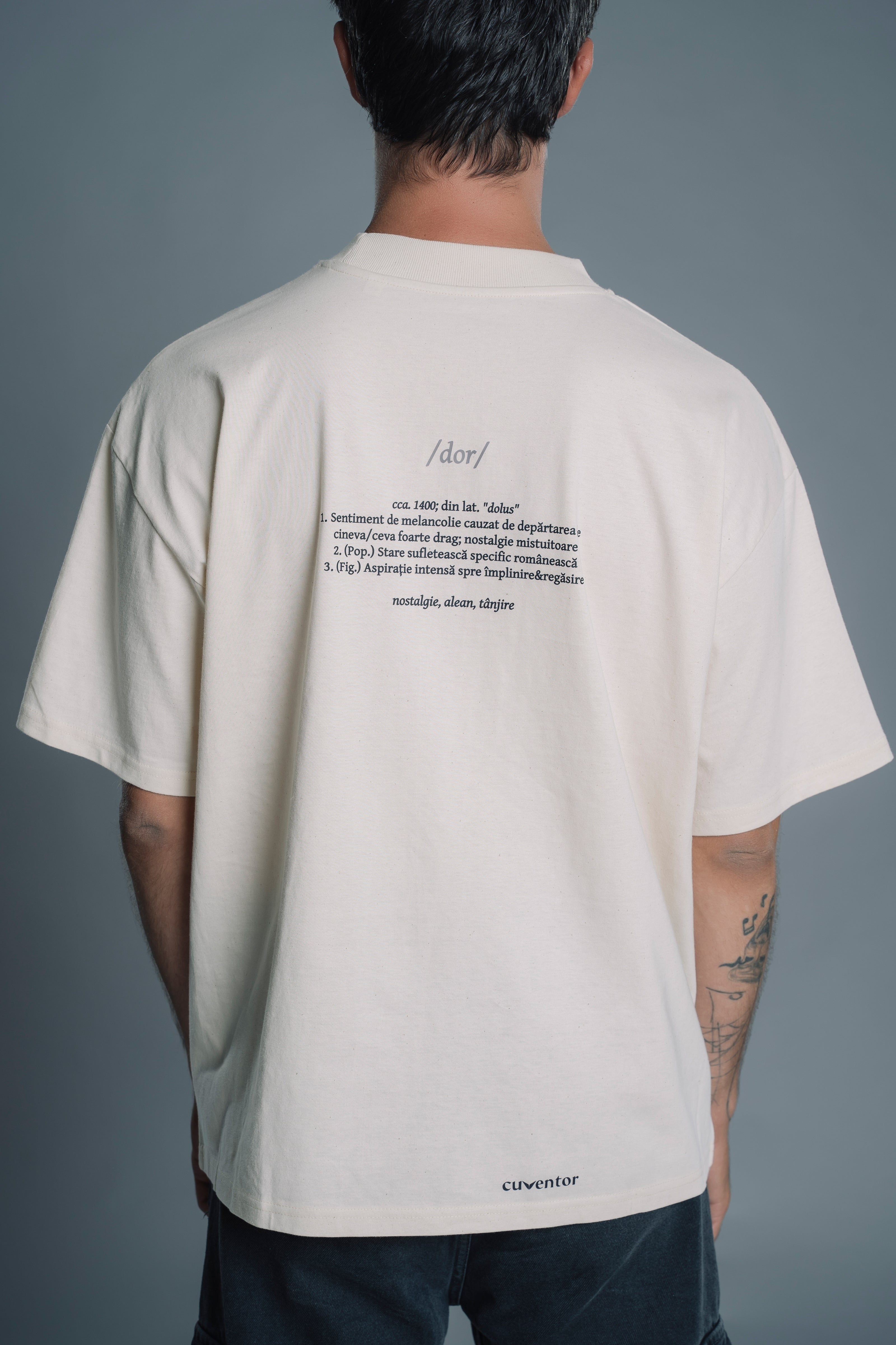 Person wearing a Natural RAW t-shirt with text on the back against a gray background