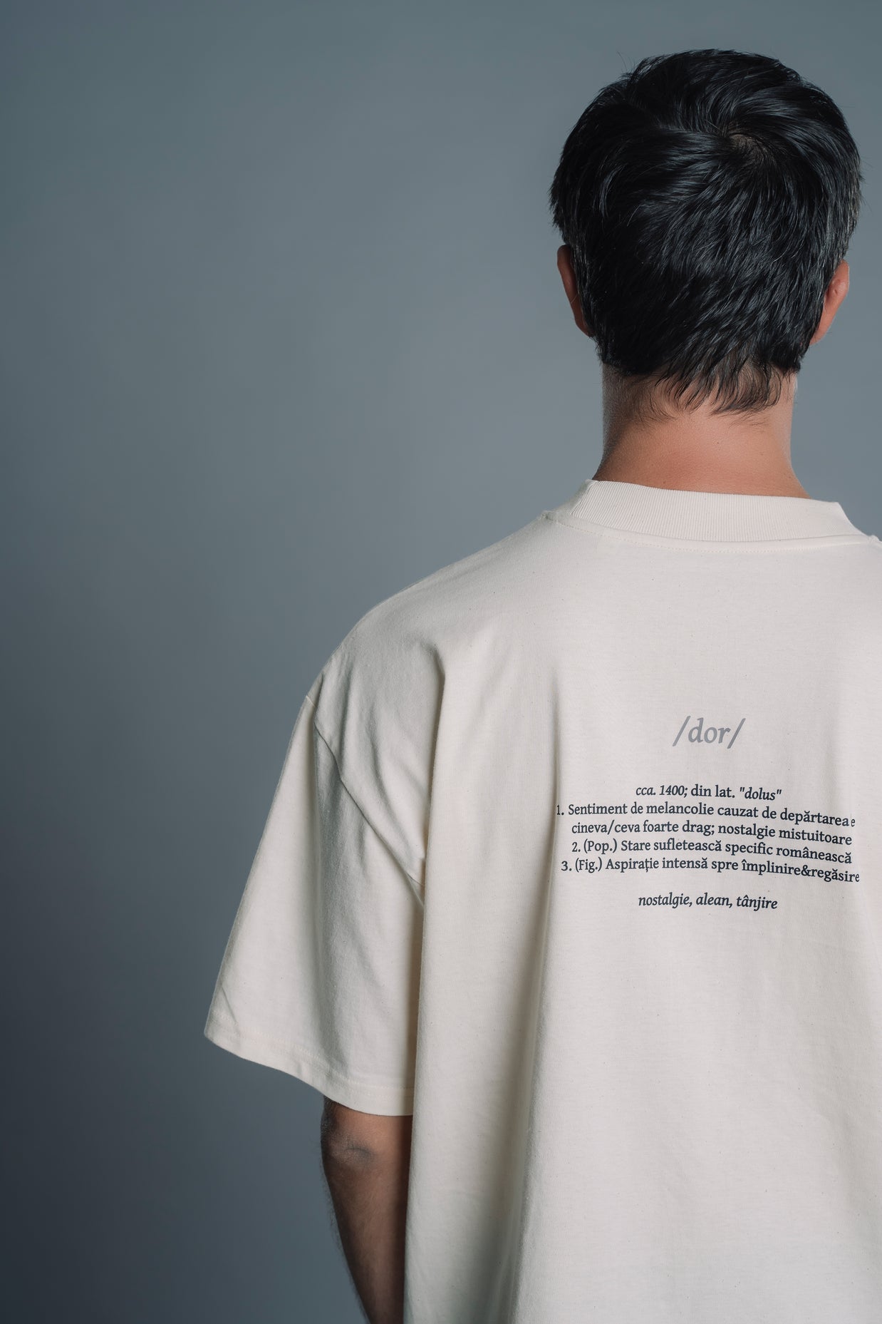Person wearing a Natural RAW t-shirt with text on the back against a gray background