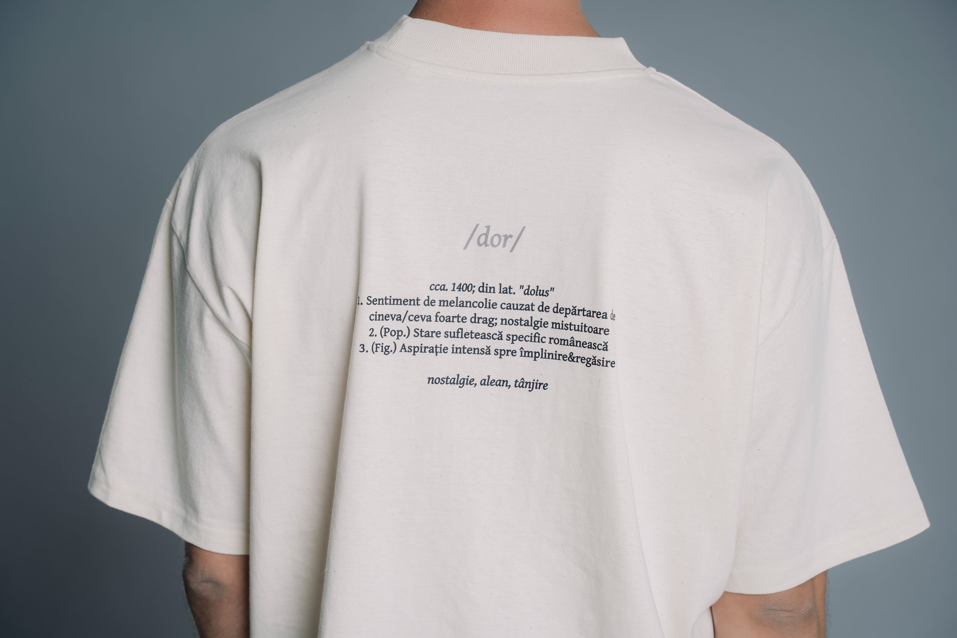 Person wearing a Natural RAW t-shirt with text on the back against a gray background